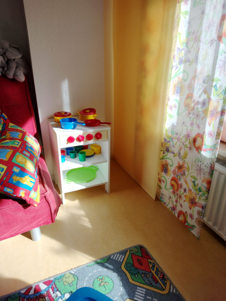 Kinderküchenutensilien und Ecke eines Sofas